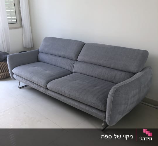 ספה אפורה על רצפה בהירה ליד חלון
